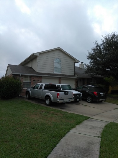 Two story home with trucks in the driveway during a roof inspection